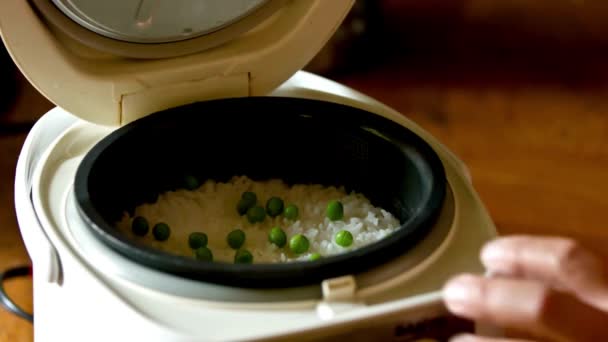 エレクトリックライスクッカーのグリーンピースでホワイトライスを調理 4Kビデオ — ストック動画