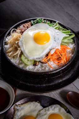 Sizzling Bi Bim Bap: 4K Ultra HD Üst Görünüm, Karışık Sebzeler, Pirinç ve Dökme Demir Tencerede Sıcak Sos