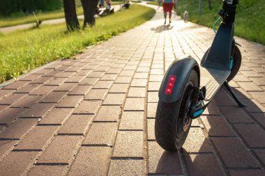 Gün batımında parktaki yolda elektrikli bir scooter 'ın yakın çekimi. Çevre dostu ulaşım.