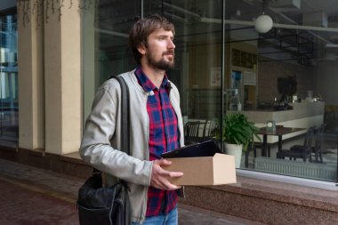 Ofiste çalışan genç adam elinde belgelerle sokakta yürüyor. Kriz, işsizlik, serbest çalışma, yaşam tarzı