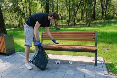 Bir gönüllü parkta plastik çöp torbaları topluyor. Ekoloji kavramı, çevre kirliliği sorunları