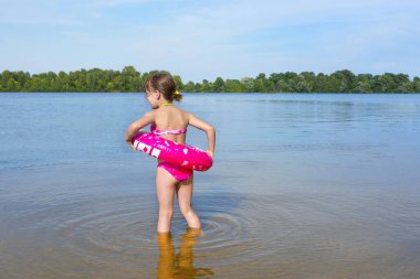Güneşli bir günde plajda lastik yüzüklü bir çocuk. Arkadan manzara..