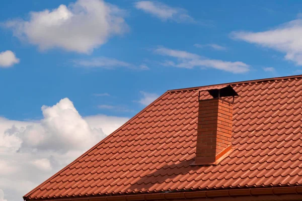 茶色のタイル張りの屋根と空に対する煙突を持つ家の一部 金属屋根 — ストック写真