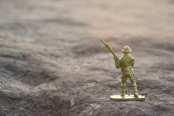 An image of an armed toy soldier outdoors. War concept, Soldier with shallow depth of field. Back view