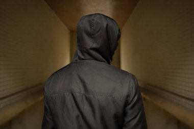 Sokakta kapüşonlu bir adam. Sosyal sorunlar, uyuşturucu bağımlılığı ve suç faaliyetleri. Arkadan manzara..