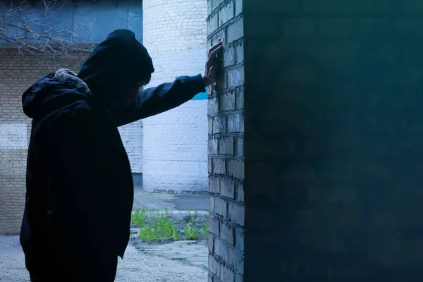 Stock image Silhouette of a man standing against a wall. The fight against crime and drug addiction. Social problems.