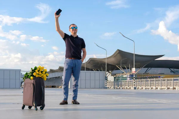 带着鲜花和手提箱的快乐男人在机场停车场遇见了乘客 旅行概念 — 图库照片
