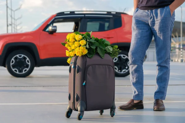 一个拿着行李和一束鲜花的男人在停车场里的剪影 休假概念 — 图库照片