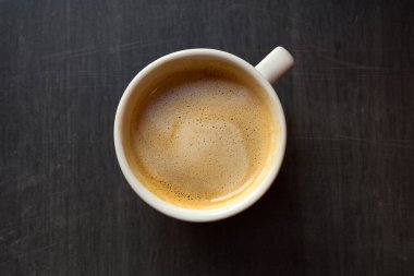 Tahta bir masanın üzerinde bir fincan kahve, yakın plan. Üst görünüm.