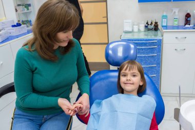 Kızıyla dişçiye giden bir anne. Anne kızının elini tutuyor..