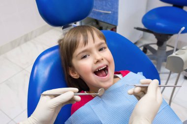 Bir dişçinin elleri ve ağzı açık bir çocuğun yakın çekimi..