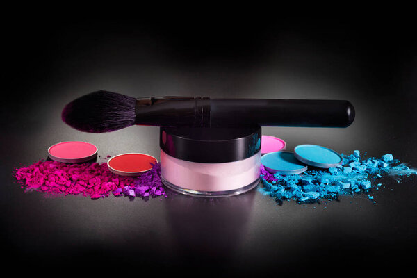 Makeup brushes and colorful eyeshadows on a black background. Professional makeup equipment. Beauty and fashion concept.