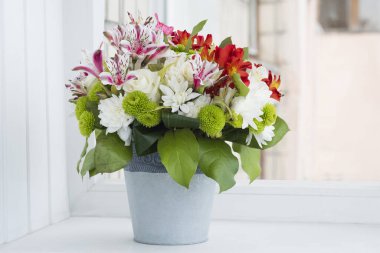 Pencere pervazında sepetin içinde güzel bir buket çiçek..