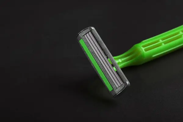 Disposable plastic razor on a black background. Close-up. Skin care concept.