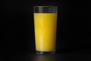 Siyah arka planda bir bardak taze portakal suyu, yakın plan..