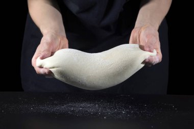 Kadın eli hamuru siyah bir masada yoğurur. Yiyecek konsepti.