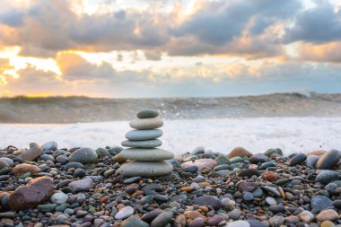 Günbatımında deniz kıyısında uzanan meditasyon için taş bir piramit..