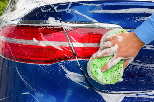 拿着海绵的人的手 洗蓝色的车 后续行动 — 图库照片