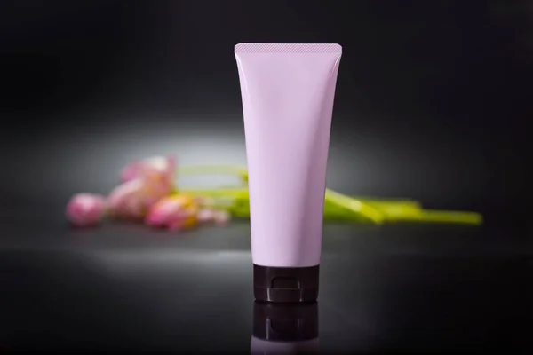Kosmetyczna Plastikowa Butelka Kosmetykami Tle Kwiatów Ciemnego Tła Pomysł Reklamę — Zdjęcie stockowe