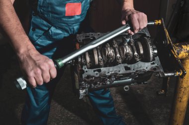 A mechanic with a wrench is repairing a car engine. Car maintenance concept. clipart