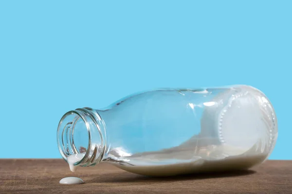 Tomma Flaska Och Droppar Mjölk Blå Bakgrund Närbild — Stockfoto