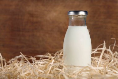 Ahşap arka planda samanlıkta bir şişe taze süt. Sağlıklı yiyecekler. Süt ürünü.