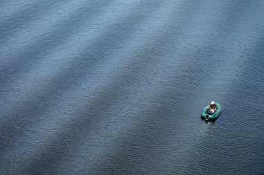 Lastik bir teknede bir balıkçı dalgalarla nehirde balık tutuyor. Yukarıdan bak, yaşam tarzı
