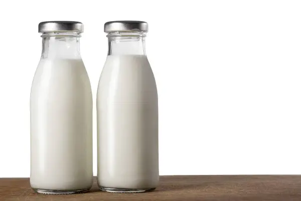 Δύο Μπουκάλια Γάλα Ένα Ξύλινο Τραπέζι Απομονωμένο Λευκό — Φωτογραφία Αρχείου
