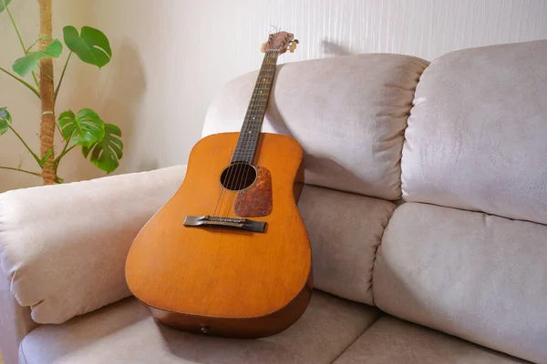 Παλιά Ακουστική Κιθάρα Ξαπλωμένη Στον Καναπέ Στο Σαλόνι — Φωτογραφία Αρχείου