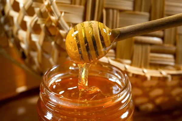 Honey drips from the honey bucket into the jar. Close-up. Healthy organic thick honey.