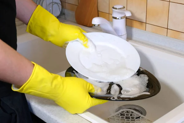 Hands with a sponge wash the dish under running water. Washing dishes during house cleaning.