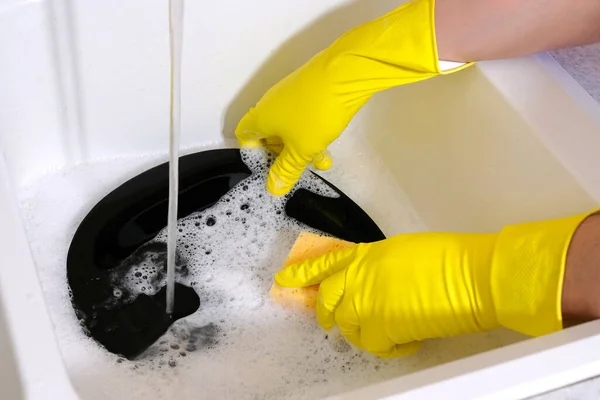 Washing dishes during house cleaning. Hands with a sponge wash the dish under running water.