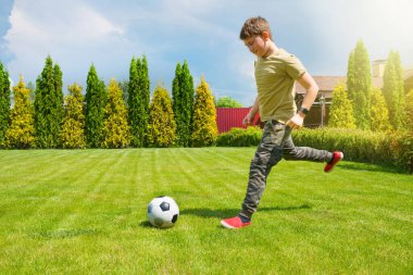 11 yaşında bir genç evin arka bahçesinde futbol oynuyor. Spor yaşam tarzı.