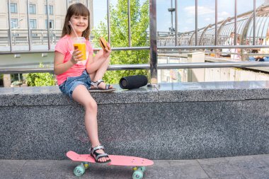Bir çocuk çizburger ve portakal suyuyla korkuluğa oturur. Bir kız dinleniyor ve kaykayla spora gittikten sonra müzik dinliyor..