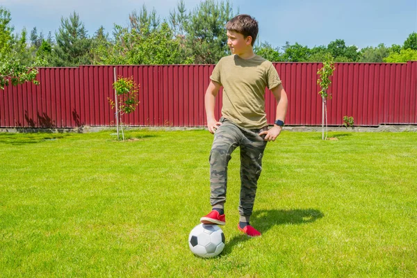 A boy with a ball in the backyard on a sunny summer day. Sport games. Healthy lifestyle concept.