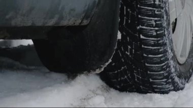 Karda araba. Karlı bir yolda lastikler kayar. Kar bir aracın dönen çarkından yükseliyor..