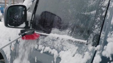 Soğuk bir kış gününde bir arabayı kardan fırçayla temizlemek. Kış mevsimi.