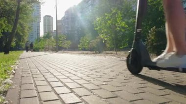 Güneşli bir günde modern bir scooterla şehir yolunda giden bir adam. Kentsel yaşam tarzı, ekolojik ulaşım.