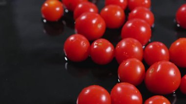 Kırmızı domatesler siyah ıslak mutfak masasında suyla..