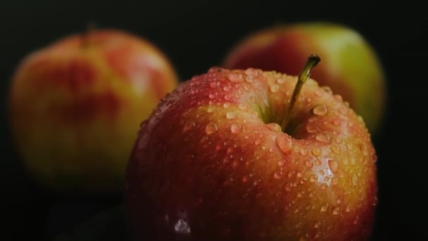 Ein Apfel Mit Wassertropfen Dreht Sich Langsam Auf Schwarzem Hintergrund — Stockvideo