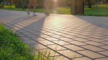 Güneşli bir günde gün batımında parkta yürüyen insanların alt görüntüsü. Etkin yaşam biçimi