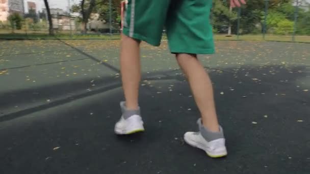 バスケットボールで都市の遊び場で運動するショートパンツの若いバスケットボール選手 スポーツライフスタイル — ストック動画