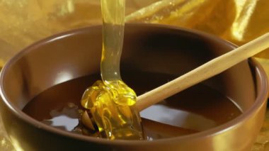 Bir kepçeyle bir kaseye dökülen balın yavaş hareketi. Bal damlaları, sağlıklı organik kalın bal. Sağlıklı gıda konsepti.
