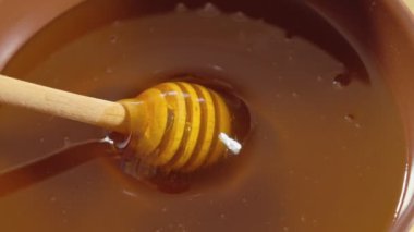 Bal damlıyor, ahşap kaseye bal damlatıyor. Tahta bal kaşığından batırılan sağlıklı organik bal, yakın plan..