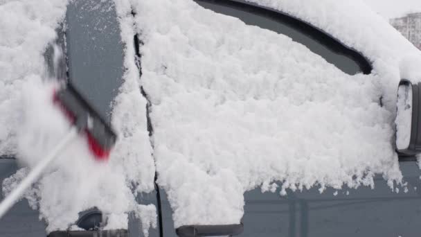 男人用刷子刷洗车上的新雪 街上到处都是雪和漂流 汽车维修 — 图库视频影像
