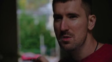 Akşam sokakta sigara içen genç bir adamın portresi. Sağlıksız yaşam tarzı kavramı.