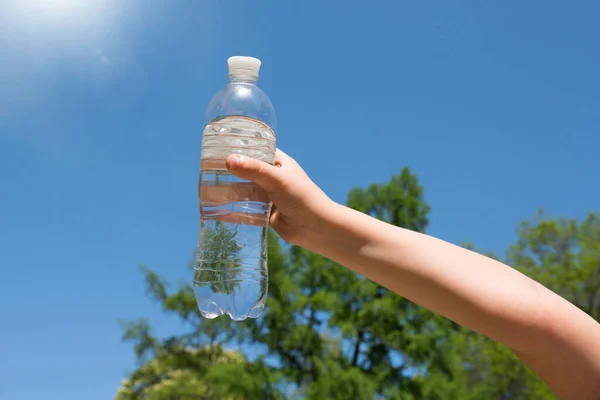 Die Hand Eines Kindes Hält Eine Flasche Trinkwasser Gegen Den — Stockfoto
