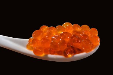 Kırmızı havyarı siyah izole arka planda bir kaşıkta yakın çekim yapın. deniz ürünleri.