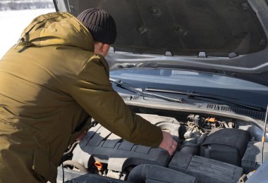 Genç adam arabasının kaputunu açtı ve bir arıza aradı..