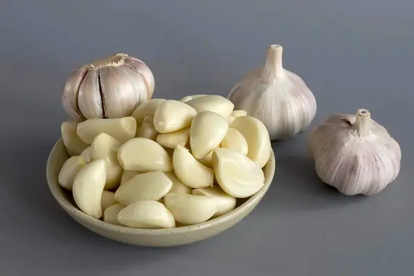 Sarımsak kabuğunun içinde, gri bir arka planda..